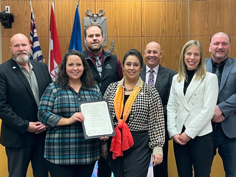 A group of people in a wood-paneled room. They are all smiling at the camera