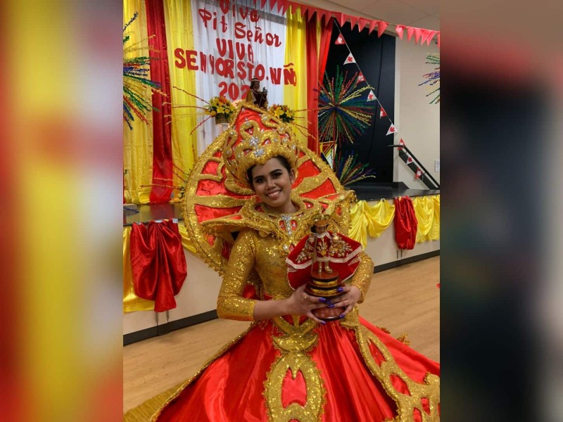 A dancer in a red dress holding a statue representing the Holy Child.