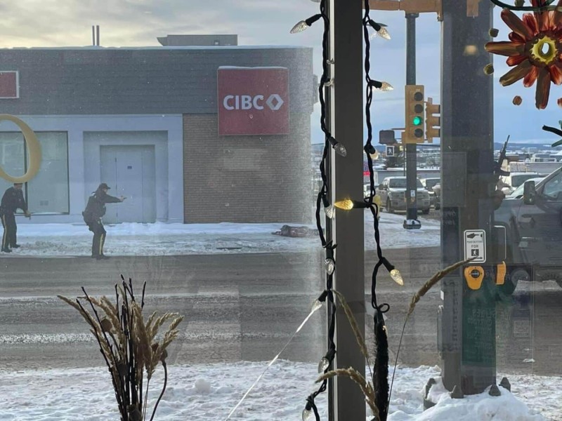 Three RCMP officers arrest a man. All three officers have handguns drawn