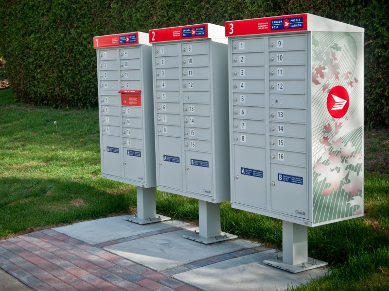 Canada Post Community Mailboxes in front of bushes.