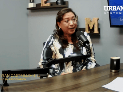 Woman at desk behind speaking into microphone