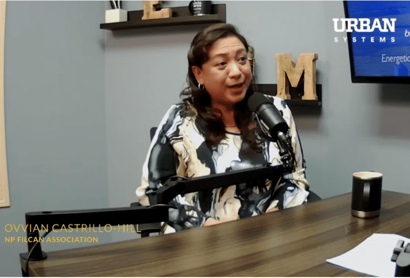 Woman at desk behind speaking into microphone