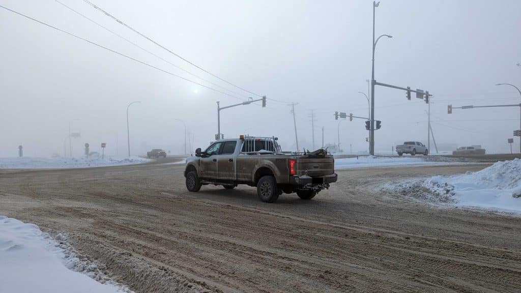 A foggy intersection of roads. Overcast with multiple cars in the image