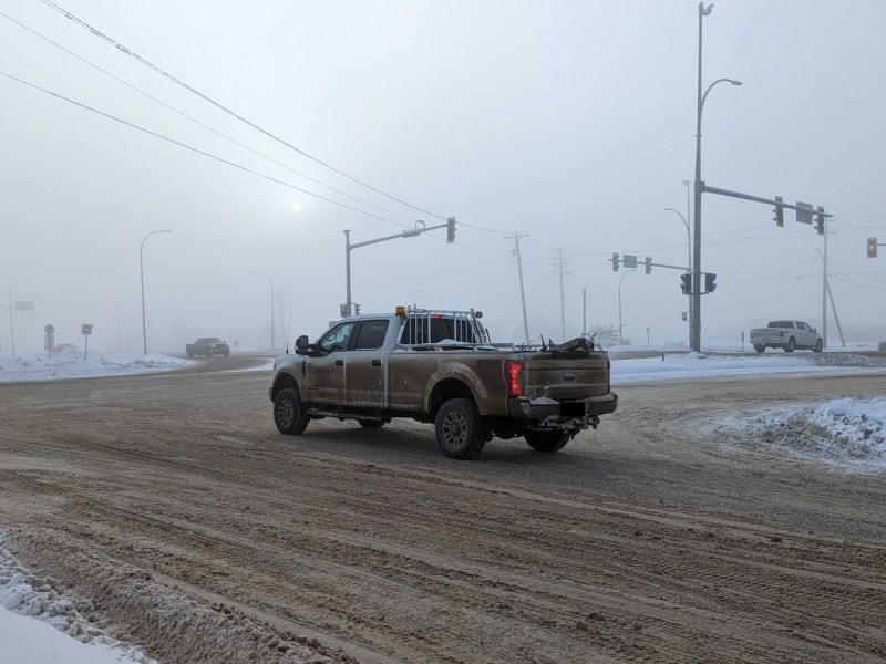 A foggy intersection of roads. Overcast with multiple cars in the image