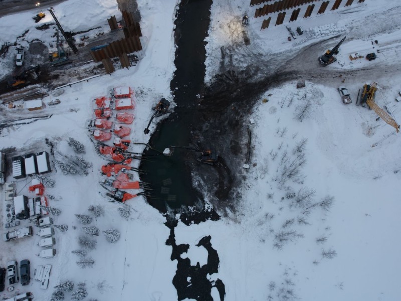 CGL Construction along the Clore river. A snowy river bank with construction equipment and material on the banks of the river. Taken from above the site.