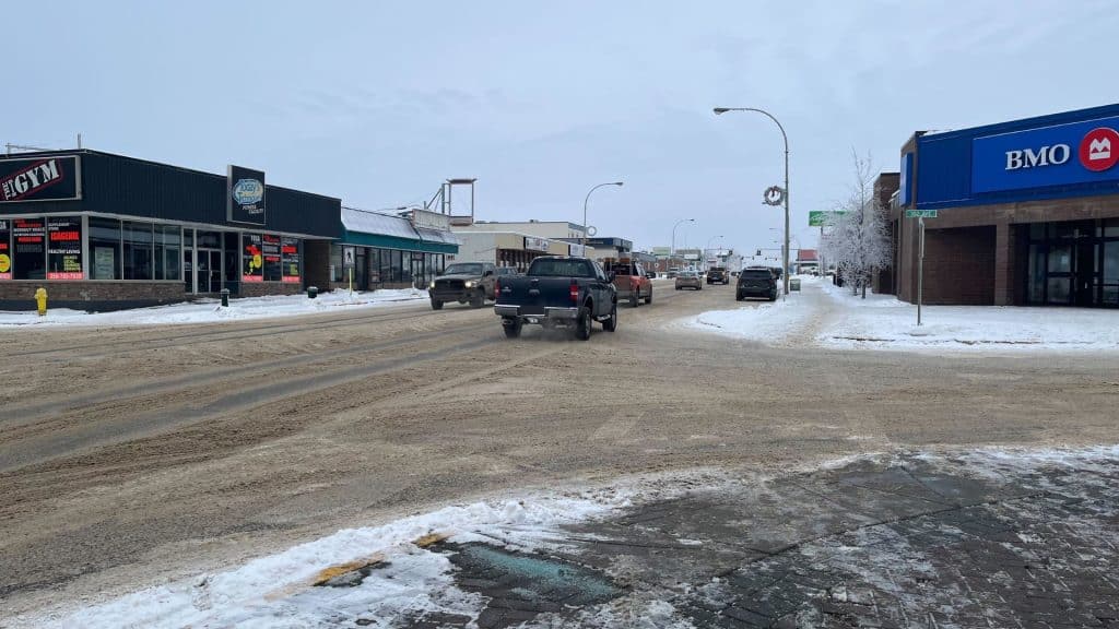 100th Street in Fort St. John. A city road covered in snow and slush with multiple cars and trucks on it.