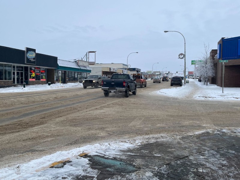 100th Street in Fort St. John. A city road covered in snow and slush with multiple cars and trucks on it.
