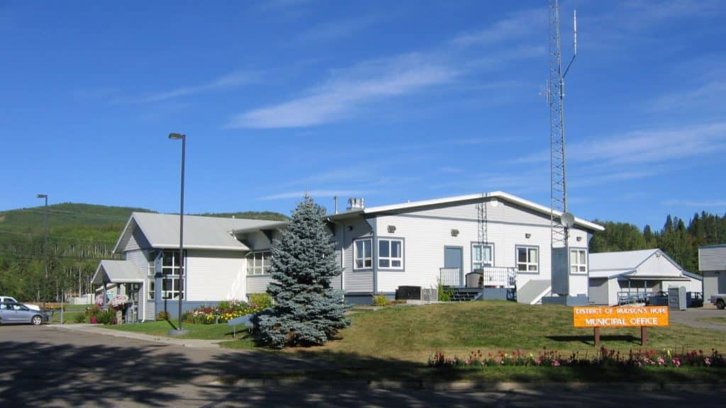 A large, white building with trees in the yard.