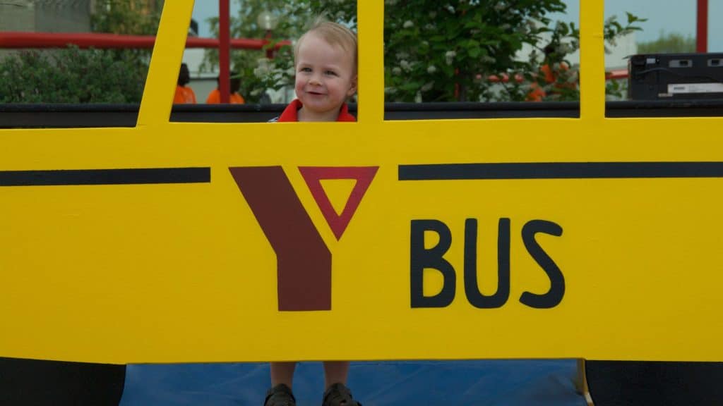 A little boy peeks through the window of a paper bus.