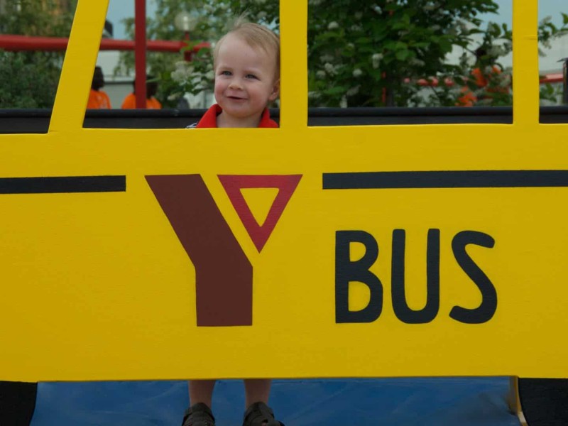 Young child with a yellow YMCA paper school bus