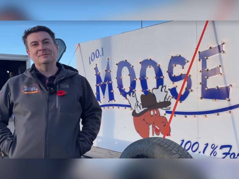 Adam Reaburn standing in front of the Light a Moose sign. (Jordan Prentice)