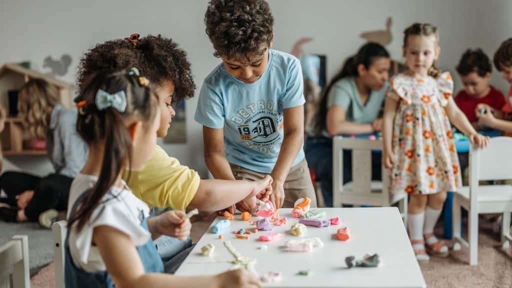 Children playing at a white table. (Canva)