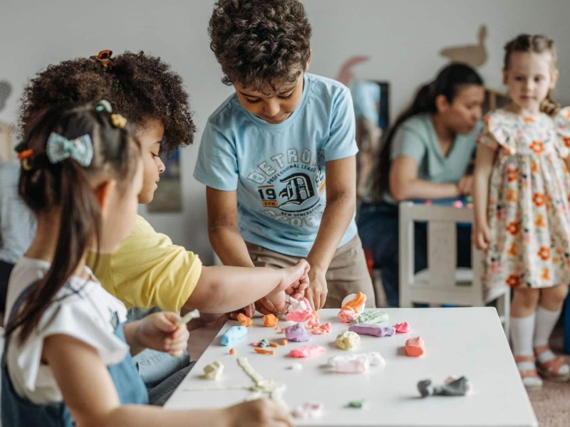 Children playing at a white table. (Canva)