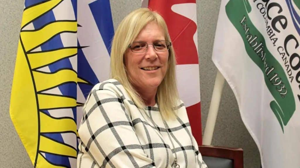 Former Pouce Coupe mayor Lorraine Michetti in front of flags at Pouce Coupe Town Hall.