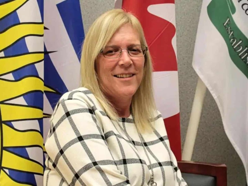 Former Pouce Coupe mayor Lorraine Michetti in front of flags at Pouce Coupe Town Hall.