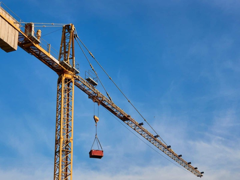 A crane up against a blue sky with some clouds.