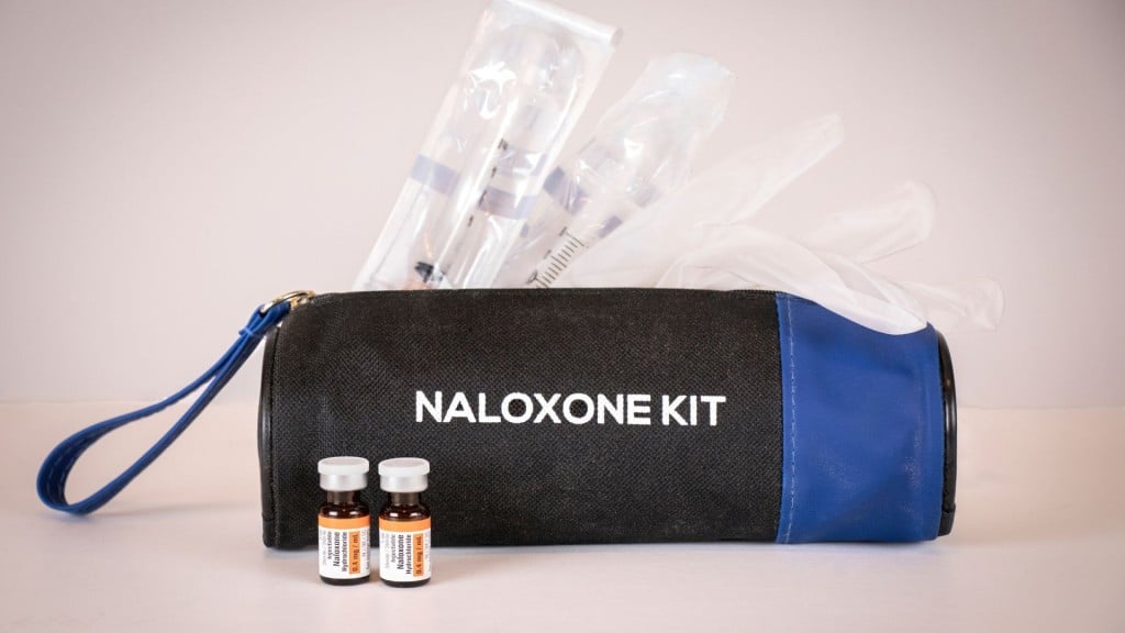A naloxone kit on a white background with pieces of the kit sticking out of a black bag.