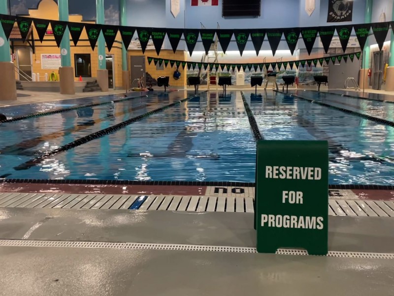 A photo of a lap pool with a green sign in front of it that reads "Reserved For Programs."
