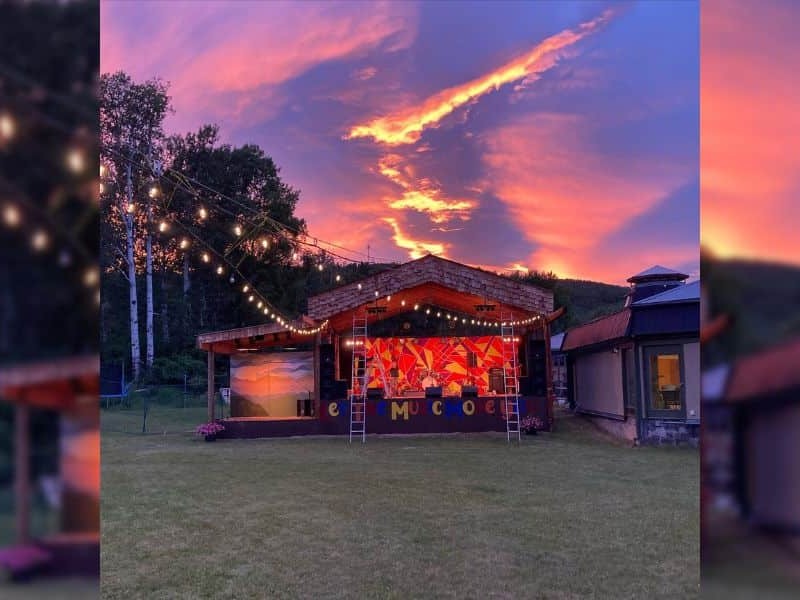 An outdoor concert at night. Pink and purple lighting from the stage.