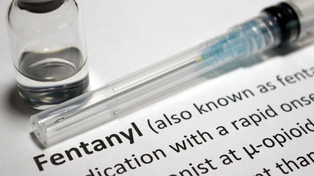 A needle and vial sitting next to a definition of fentanyl.