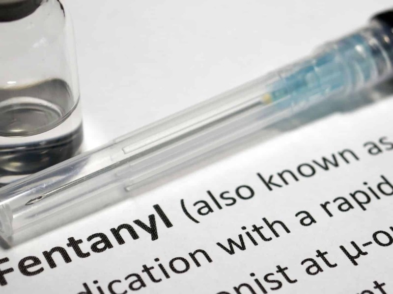 A needle and vial sitting next to a definition of fentanyl.