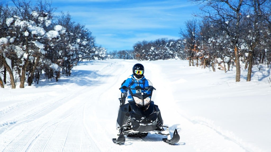 A snowmobile on a trail surrounded by trees.