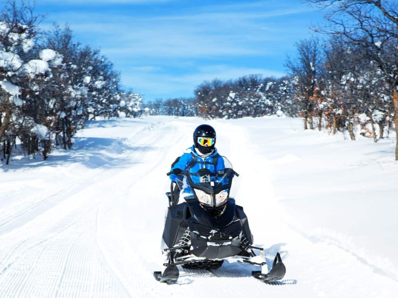 A snowmobile on a trail surrounded by trees.