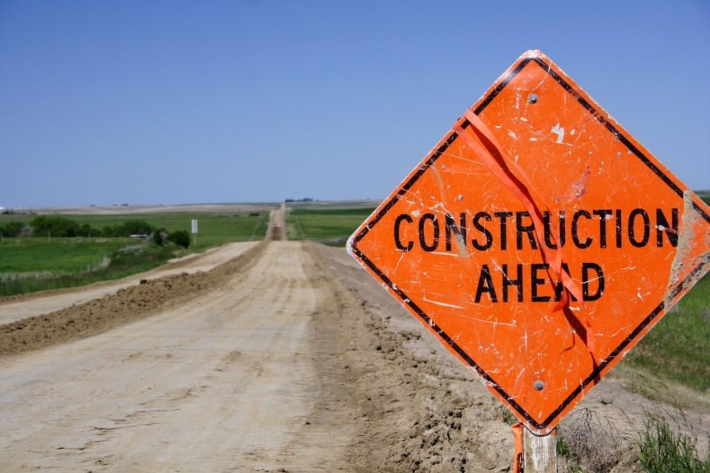 A "Construction Ahead" sign on a dirt road.