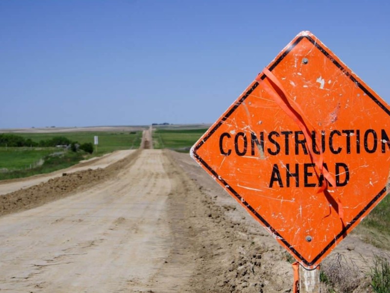 A "Construction Ahead" sign on a dirt road.