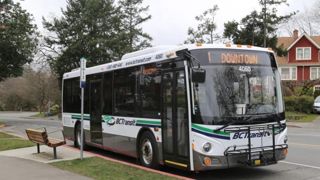 A white BC Transit bus with green and blue waves on it.
