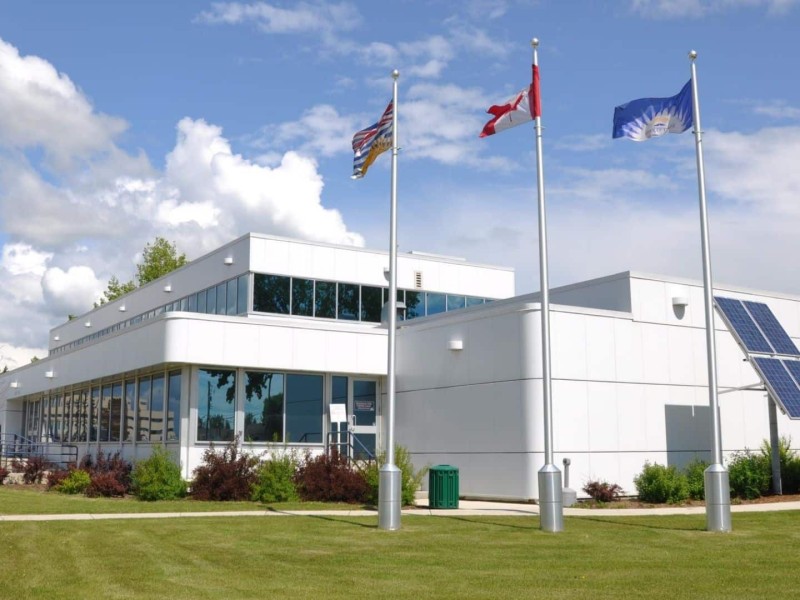 Fort St. John City Hall. A large white building with three flag poles and flags in front of it.