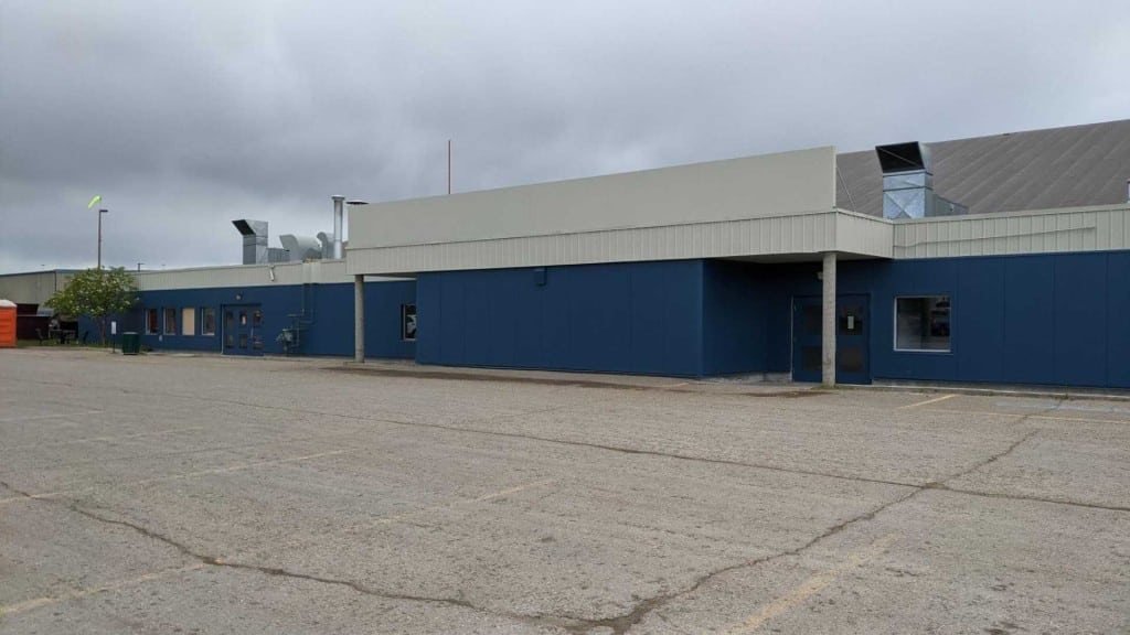 A picture of a blue building in an empty parking lot under a grey sky.