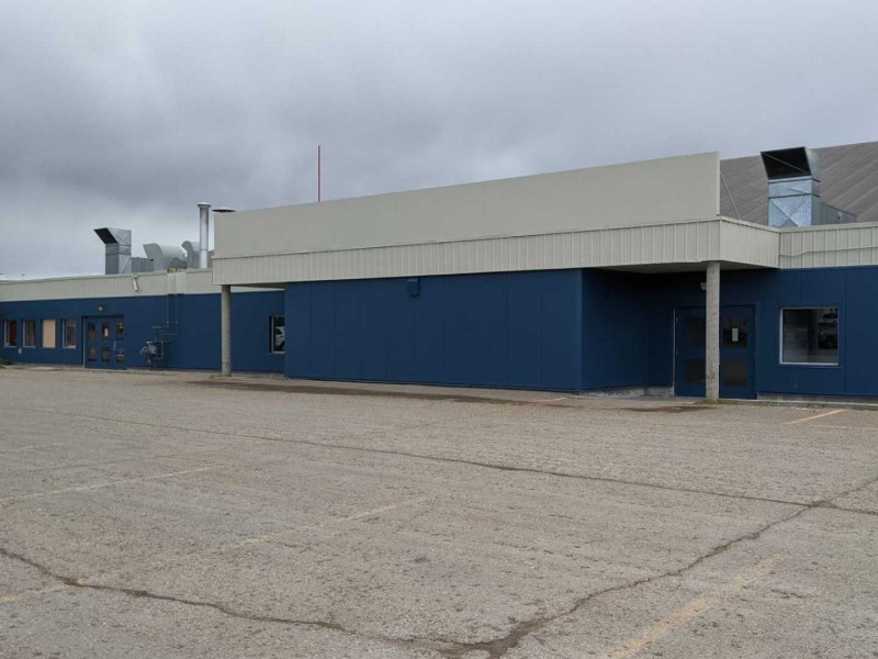 A picture of a blue building in an empty parking lot under a grey sky.