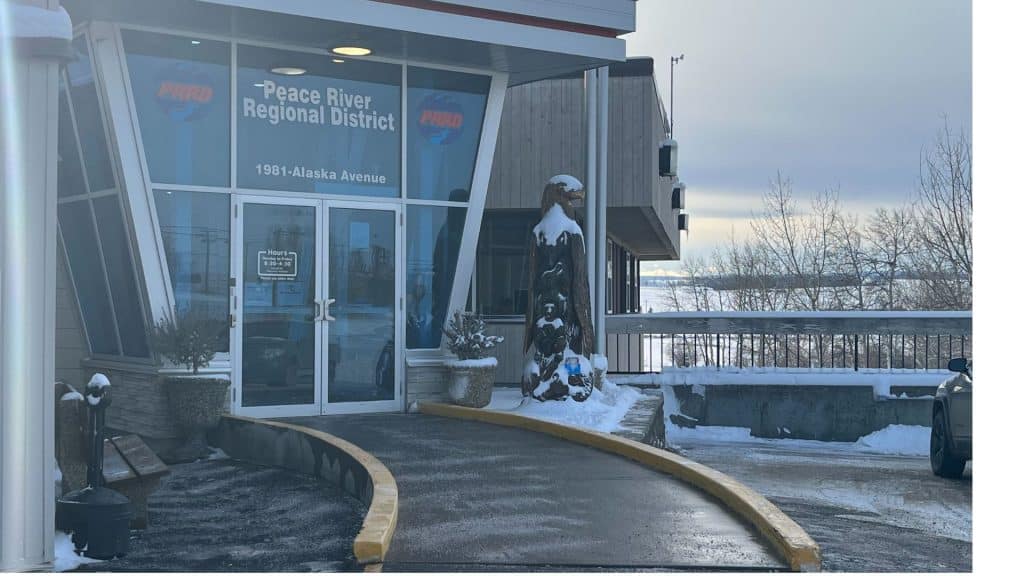 A glass building with a wooden statue of a bird next to the door.