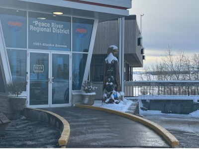 A glass building with a wooden statue of a bird next to the door.
