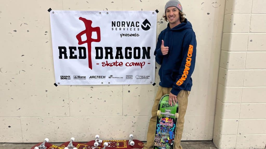 A man in a blue and orange hoodie, giving a thumbs up towards the camera.