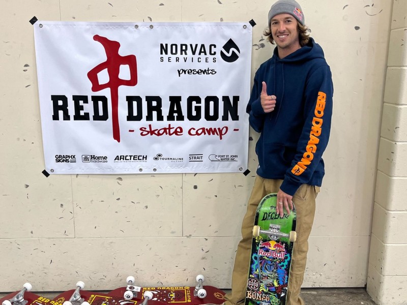 A man in a blue and orange hoodie, giving a thumbs up towards the camera.