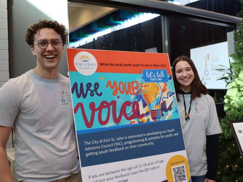 A pair of highschool students next to a sign for the Youth Changing Tomorrow conference.