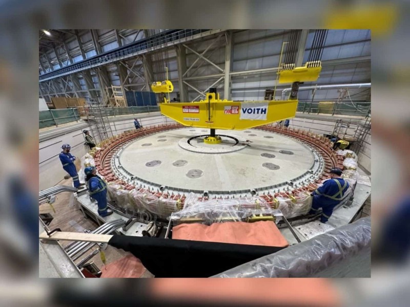 Workers standing around a 600-tonne rotor being lifted into place inside Site C.