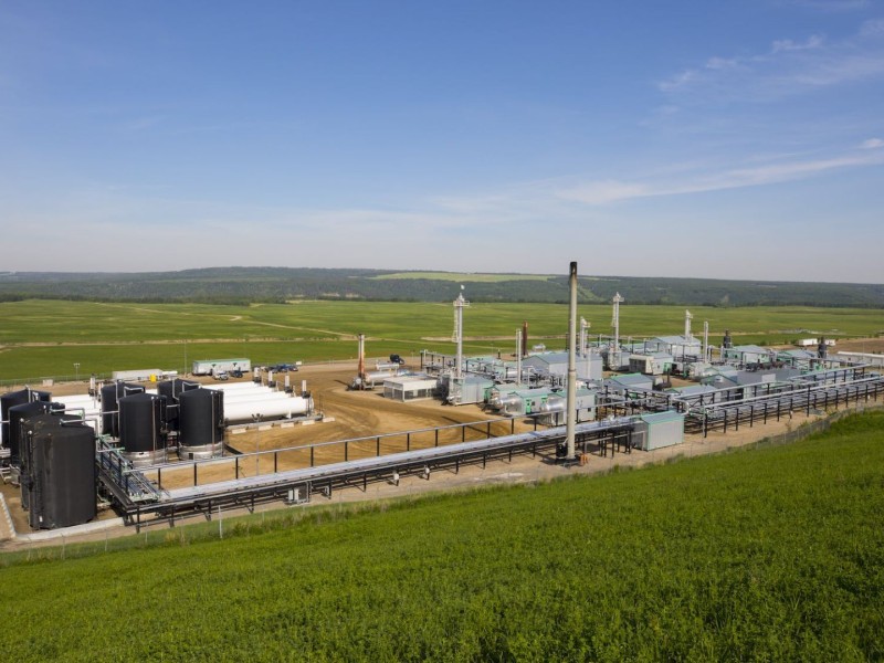 A natural gas well in a large, green, open field.