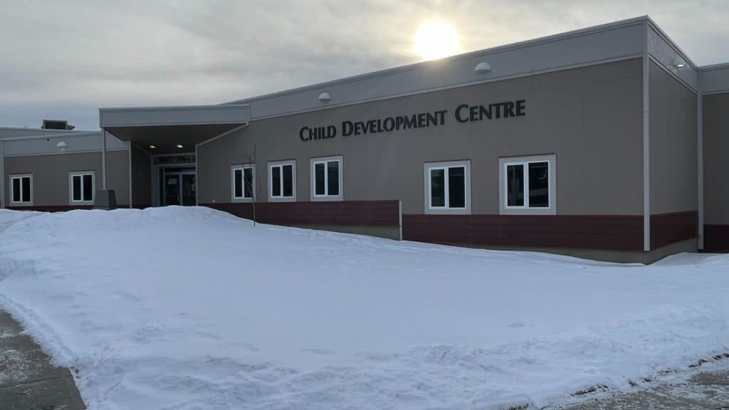 A Child Development Centre grey building with snow and a sun in the background.