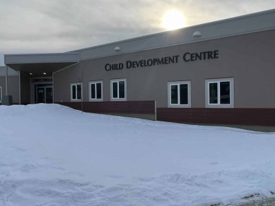 A Child Development Centre grey building with snow and a sun in the background.