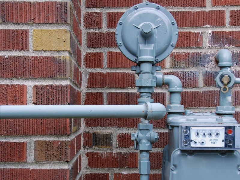 A picture of a grey gas meter on a brick building.