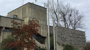 The Provincial Government Building and Law Courts sign in front of the grey brick building.