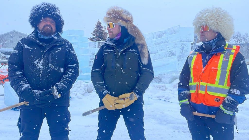 Three men in warm winter gear standing in front of blocks of ice.