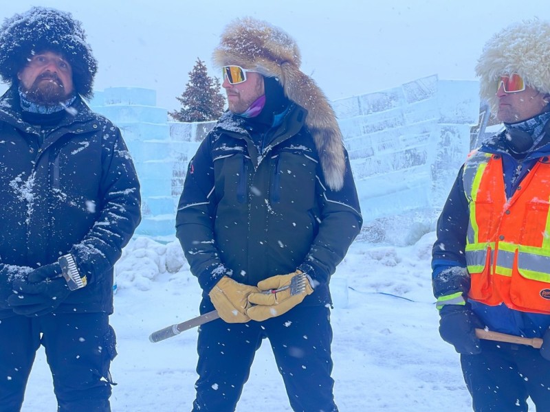 Three men in warm winter gear standing in front of blocks of ice.