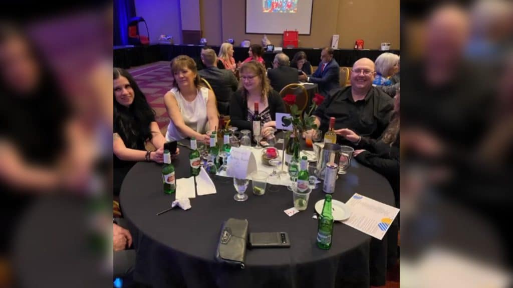 A group of people sitting around a dinner table in a decorated hall.