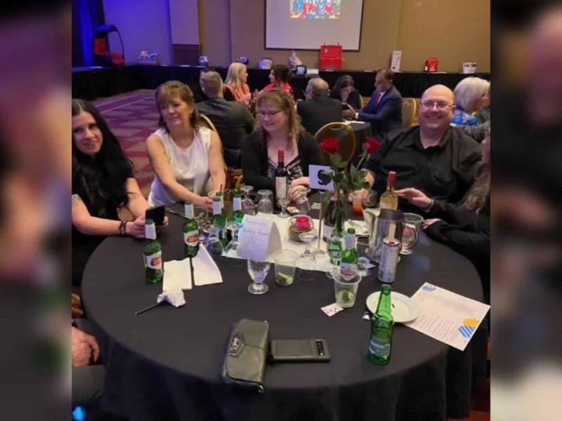 A group of people sitting around a dinner table in a decorated hall.