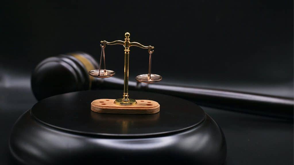 A black gavel and small set of golden justice scales.
