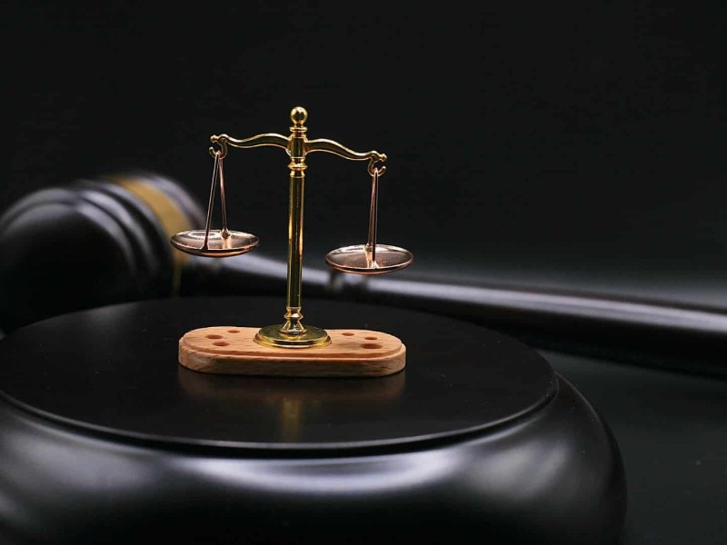 A black gavel and small set of golden justice scales.